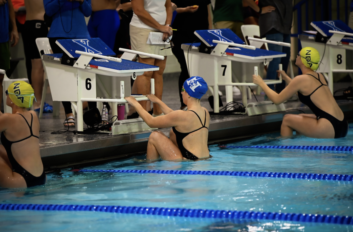 Sarah Jones (12) holds on to the starting block while she waits for her 100 yard backstroke to begin.